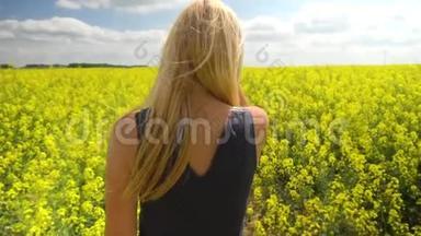 年轻的金发女人在美丽的油菜田里奔跑
